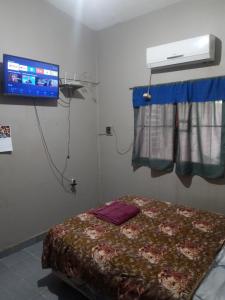 Zimmer mit einem Bett und einem TV an der Wand in der Unterkunft Casa de Fin de semana in Termas de Río Hondo