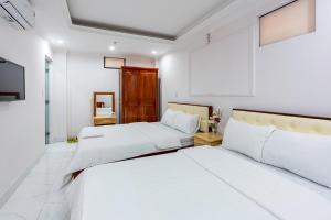 Dos camas en una habitación con paredes blancas. en Nhà Nghỉ Light Hotel, en Hanói