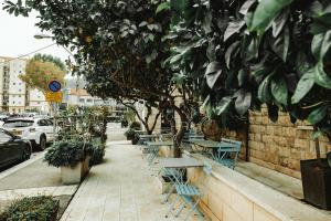 a row of tables and chairs on a sidewalk at Bat Galim Boutique Hotel in Haifa