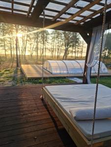 two beds on a deck with the sun in the background at Poilsiaviete Vakaris in Gudeliai