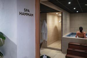 a man sitting in a bath tub in a spa hammann bathroom at Keystone Hôtel & Spa in Lyon