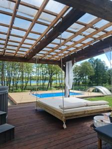 a large bed on a wooden deck with a roof at Poilsiaviete Vakaris in Gudeliai