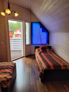 a bedroom with two beds and a large window at Saimaa Gardens Apartment near Beach in Rauha