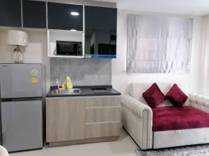 a small kitchen with a couch and a refrigerator at Gardens peace Hatyai in Hat Yai