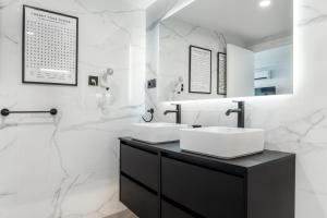 a bathroom with two sinks and white marble walls at Perla Negra - Apartment with Private Beach Access in Benalmádena +31 photos
