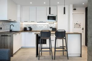 a kitchen with white cabinets and two bar stools at Perla Negra - Apartment with Private Beach Access in Benalmádena