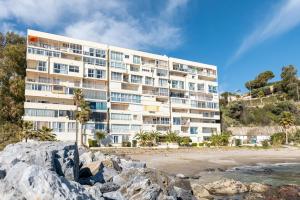 a large white building on the beach next to a beach at Perla Negra - Apartment with Private Beach Access in Benalmádena