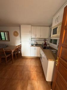 eine Küche mit weißen Schränken und einem Tisch darin in der Unterkunft Sweet Life in Costa Del Silencio + 8 Fotos