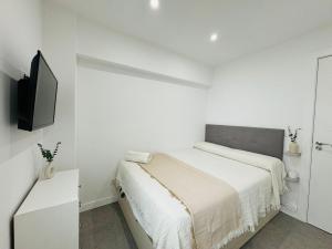 a white bedroom with a bed and a flat screen tv at Increíble piso cerca centro Málaga in Málaga