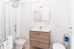 a white bathroom with a sink and a toilet at GuestHost - Scaringi Palace B in Trani +17 photos