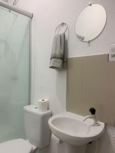 une salle de bain avec toilettes, lavabo et miroir dans l'établissement Hotel Avenida, à Ribas do Rio Pardo