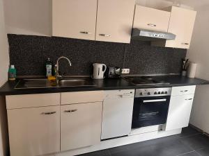 a kitchen with white cabinets and a sink and a stove at Haus mit Terrasse&Garten in Ilsede