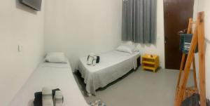 une petite chambre avec deux lits et une télévision dans l'établissement Hotel Avenida, à Ribas do Rio Pardo