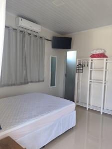 a bedroom with a white bed and a window at Recanto dos pássaros in Santa Cruz Cabrália
