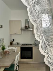 a kitchen with a table and a white curtain at La Finestrella in Giardina Gallotti