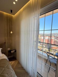 a bedroom with a large window with white curtains at Downtown Shkodra Apartment in Shkodër
