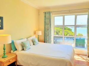 Un dormitorio con una cama con una ventana grande. en Goldwater 7, en Gordonʼs Bay
