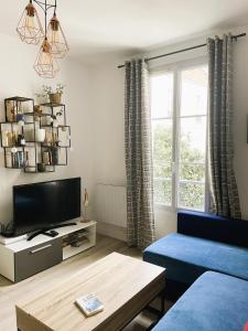 un salon avec un canapé bleu et une télévision dans l'établissement Appartement sur cour quartier Olympiades, à Paris