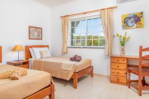 a bedroom with two beds and a desk and a window at Villa Audiência 145 in Castro Marim