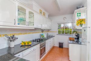 a kitchen with white cabinets and a bowl of fruit on the counter at Villa Audiência 145 in Castro Marim