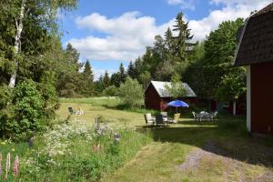 ein Garten mit Tisch und Stühlen und eine Scheune in der Unterkunft Idyllisches Landhaus mit Ruderboot, Südschweden in Vissefjärda