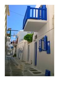 un callejón con edificios blancos con ventanas azules y balcón en Kymata en Mykonos ciudad