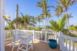 a porch with two chairs and palm trees and the ocean at Captiva Grace home in Captiva
