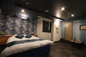 a bedroom with a large bed with a wall at Hotel京都 in Zentsuji +4 photos