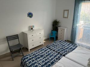 ein Schlafzimmer mit einem Bett, einem Stuhl und einer Kommode in der Unterkunft Villa 1 Minute Du Bord De Mer Jardin Clim Wifi in Santa-Lucia-di-Moriani