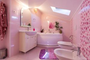 a pink bathroom with a sink and a tub and a toilet at Apartman Sara s predivnim pogledom na more in Matulji +28 photos