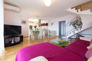 a living room with a purple couch and a tv at Apartman Sara s predivnim pogledom na more in Matulji