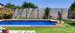 a woman is standing next to a swimming pool at Casa de totys en la Serena in La Serena