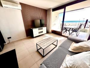 ein Wohnzimmer mit einem Sofa, einem TV und einem Tisch in der Unterkunft Apartaments Voramar in Cambrils