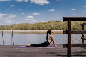 a woman doing yoga on a dock near the water at Charszówka in Kobrzyniec Stary