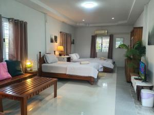 a bedroom with two beds and a table and a couch at Granny's home บ้านคุณย่า in Lampang