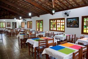 uma sala de jantar com mesas, cadeiras e janelas em Hotel Fazenda Monte Sião em Monte Sião