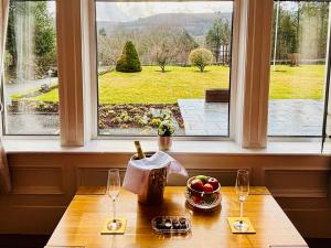un tavolo con due bicchieri e un cesto di frutta davanti a una finestra di The Claymore Guest House a Pitlochry