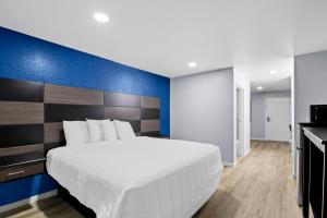 una camera da letto con un letto grande con una parete blu di Americas Best Value Inn-Gonzales a Gonzales