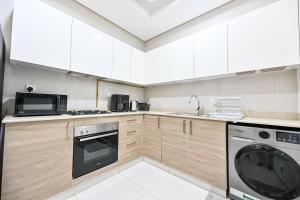 La cuisine est équipée de placards blancs et d'un lave-vaisselle. dans l'établissement Luxury 1BR Near Burj Khalifa with Canal Views, à Dubaï