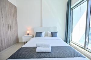 une chambre avec un grand lit blanc et une grande fenêtre dans l'établissement Luxury 1BR Near Burj Khalifa with Canal Views, à Dubaï