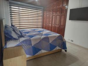 a bedroom with a bed with a blue and white comforter at El Manantial de Sopo in Sopó +6 photos