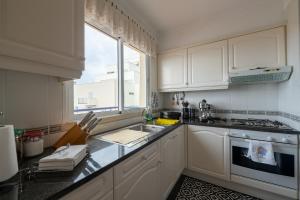 a kitchen with white cabinets and a sink and a window at Madeira Sunny Penthouse in Funchal