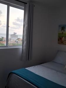 ein Schlafzimmer mit einem Bett und einem Fenster mit Aussicht in der Unterkunft Apartamento linda vista para o mar Penha Parque Beto Carrero in Penha + 11 Fotos