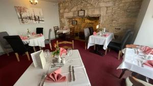 a restaurant with white tables and chairs and a stone wall at Anglebury House in Wareham