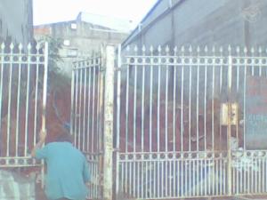 a person standing next to a metal fence at Ponto comercial, murado com grade in Itaquaquecetuba