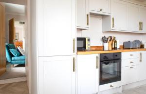a white kitchen with white cabinets and a microwave at Taigh Mhurdaidh in Culnacnoc +14 photos