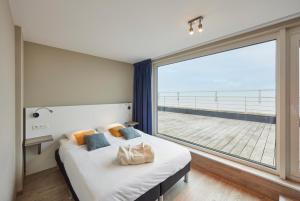 ein Schlafzimmer mit einem Bett und einem großen Fenster in der Unterkunft Holiday Suites Blankenberge in Blankenberge
