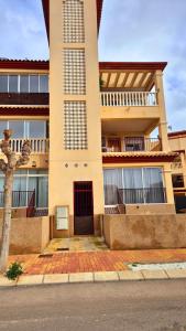 a tall building with a red door on a street at Appartement cosy avec 2 chambres et piscine commune in San Pedro del Pinatar