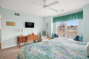 a bedroom with a bed and a desk and a tv at Seas the Day - Water views, Shared pool! in Chincoteague +28 photos