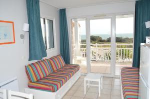 a living room with a couch and a balcony at Appartements front de mer 2 piscine chauffées la pironnière Residence de l'estrand in Les Sables-d'Olonne